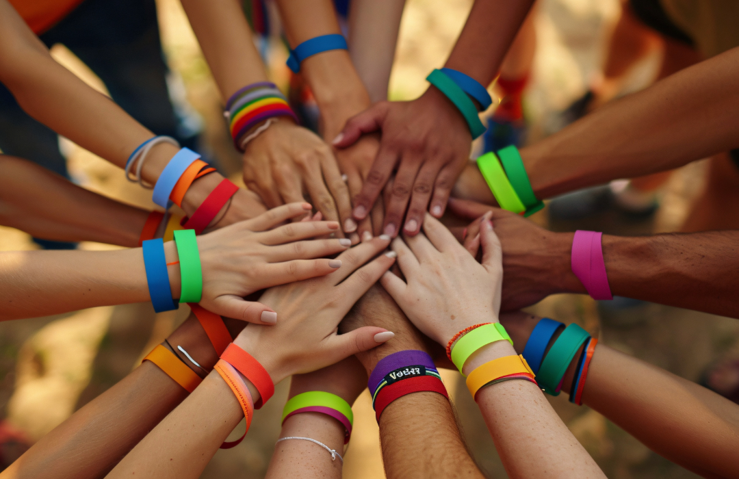 A group of different hands that have wristbands on them